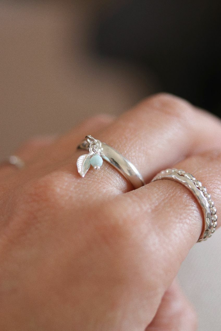 טבעת פס חלקה ודקה פתוחה מאחורה עם עלה קטן ואבן חן לרימר בצבע תכלת.jpg