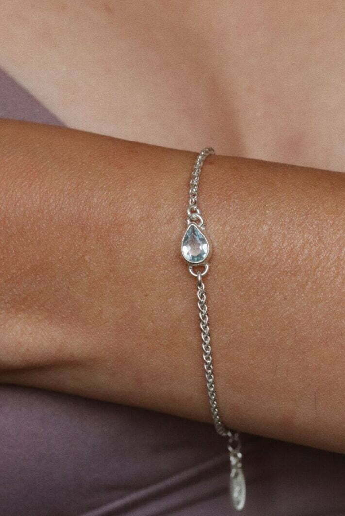 צמיד חבל עדין בשילוב אבן חן טופז טבעית בצורת טיפה ובגווני תכלת פסטלים. מיוצר מכסף 925