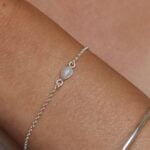 צמיד לולאות עדין בשילוב אבן חן מונסטון קטנה בצורת טיפה ובגווני לבן עם השתקפויות של צבעי קשת. מיוצר מכסף 925 ועמיד במים